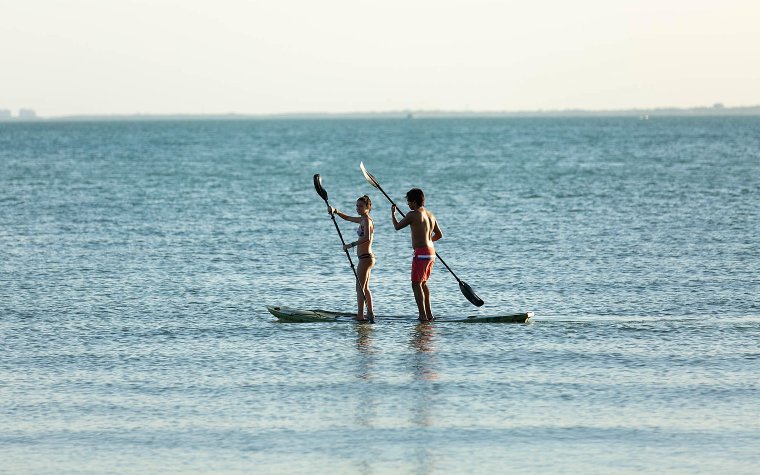 Couple doing standup paddleboarding Couple doing standup paddleboarding
