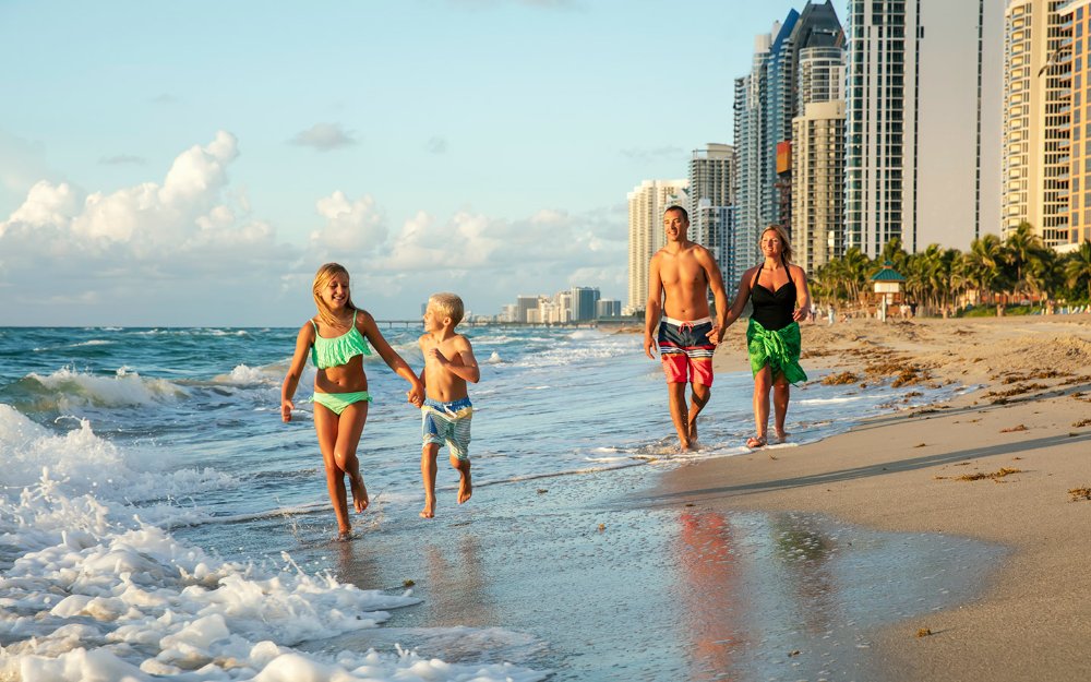 Una familia disfrutando de la costa arenosa de Sunny Isles Beach