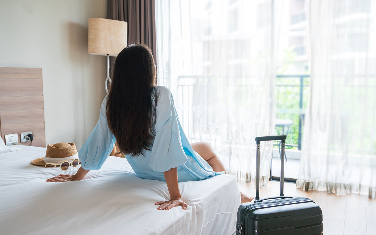 iStock_1436667024_ Hotel _room_woman_on_bed_1440x900.jpg