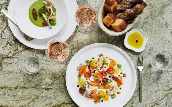 Uma mesa posta no Le Jardinier, exibindo cores vibrantes e pratos sazonais, destacando o frescor e a arte da culinária