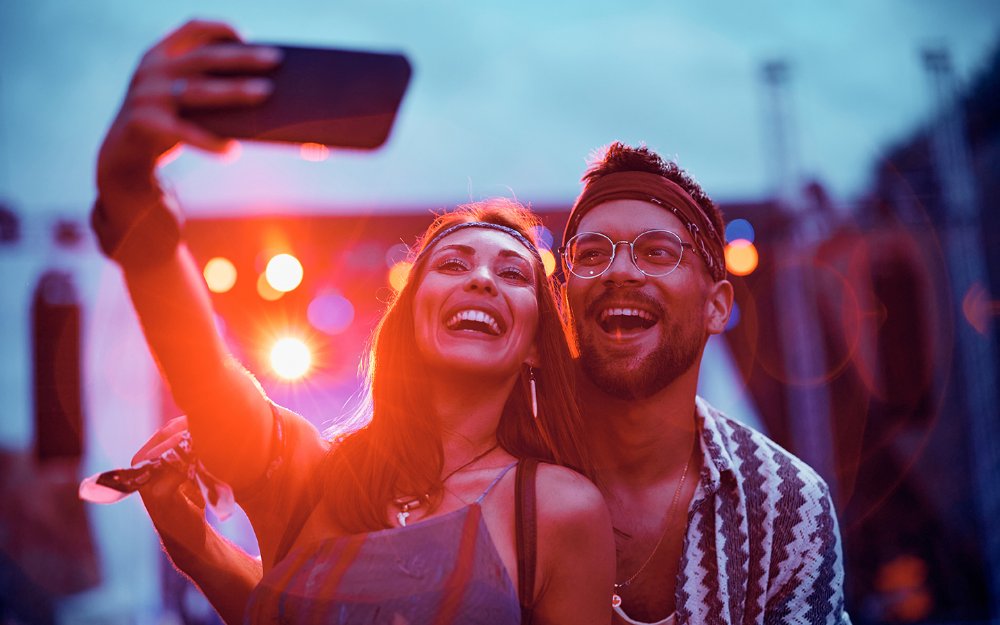 Una pareja posa para una selfie en un concierto de música en vivo.