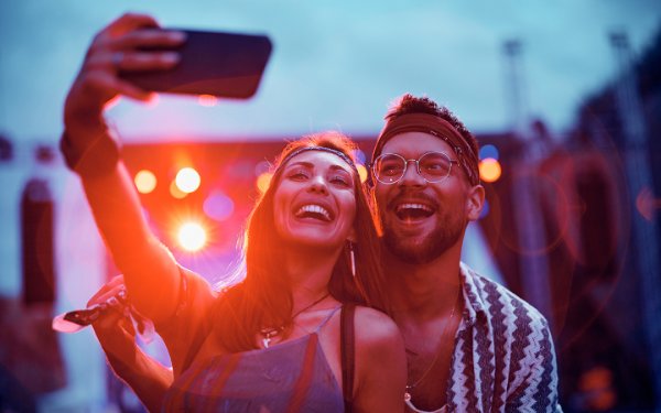 Una coppia posa per un selfie a un concerto di musica dal vivo