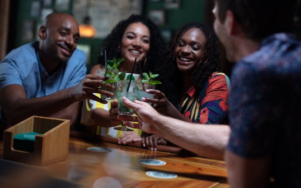 Friends raising glasses and enjoying mojitos together, celebrating and smiling in a lively atmosphere