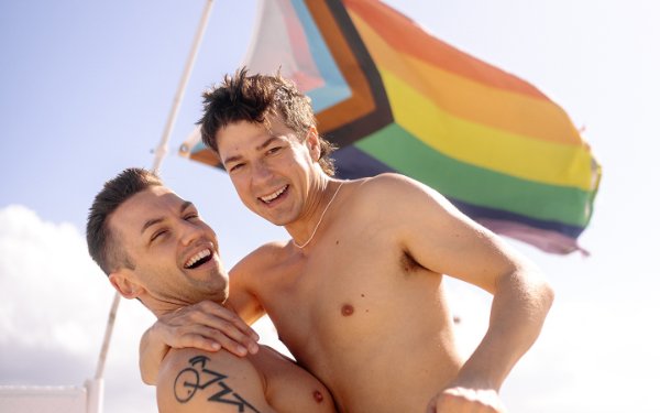 Matt y Michael de pie frente a una bandera en el Beach