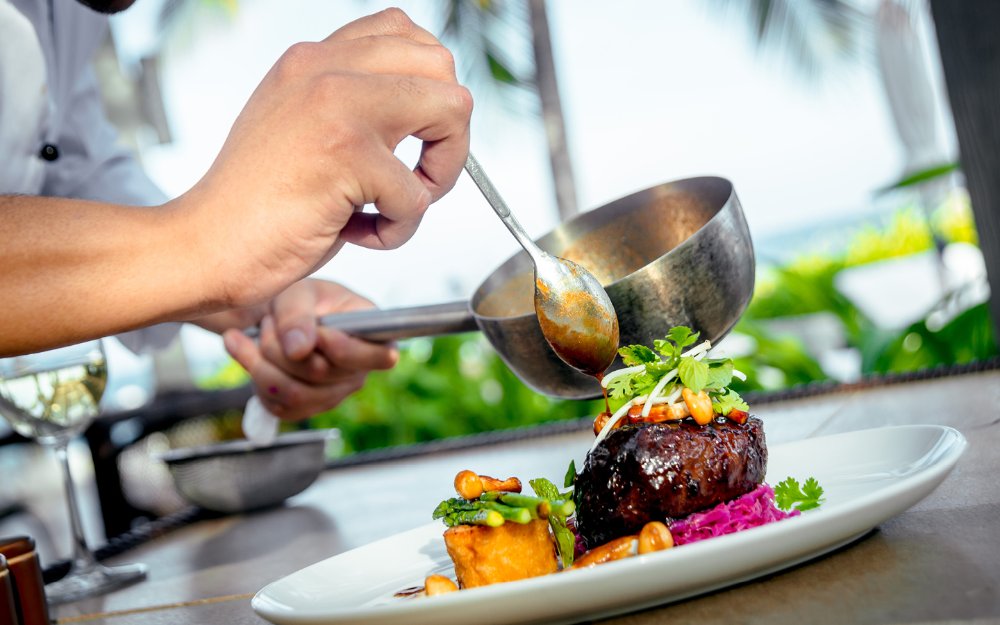 Chef despejando molho sobre bife