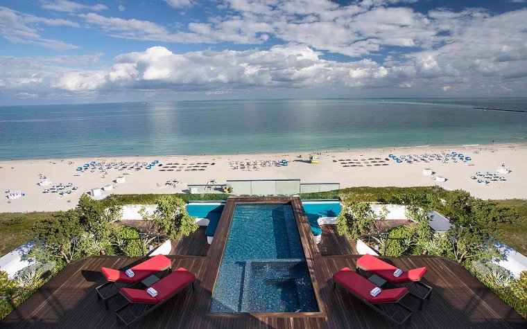 Rooftop pool at Hilton Bentley Miami South Beach with lounge chairs and beach views Rooftop pool at Hilton Bentley Miami South Beach with lounge chairs and beach views