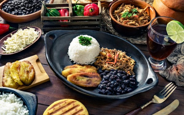 Mesa de comida mostrando muita comida latina e acompanhamentos como carne desfiada, arroz e feijão, Plaintains